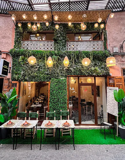The Le Vrai Traditionnel restaurant front in the Marrakech medina: a plant-covered two-storey facade with hanging rattan lanterns and traditional low tables set with tagines along the alley, the restaurant the conversion website was built for.